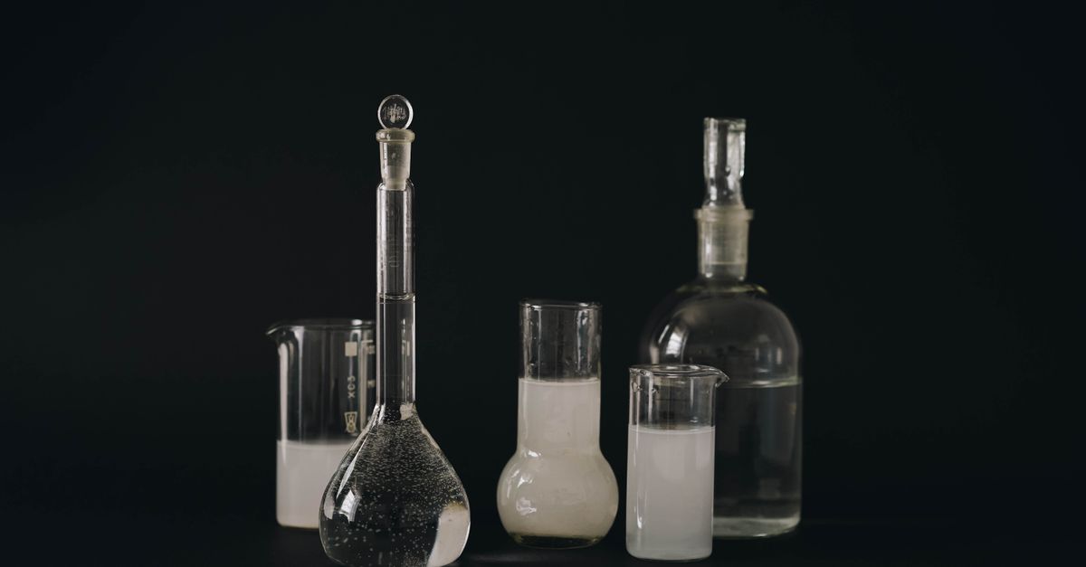 Set of glass laboratory bottles and flasks with liquids on a dark background.